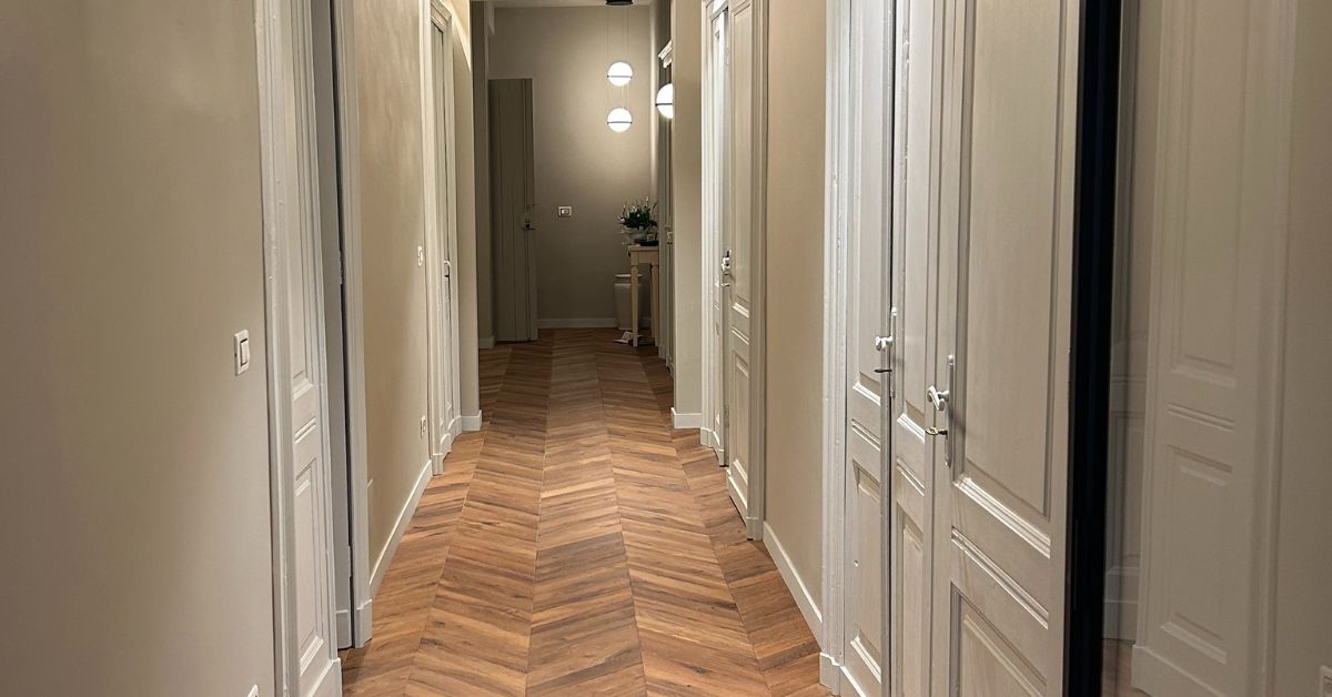 Corridoio con parquet a spina e porta in vetro